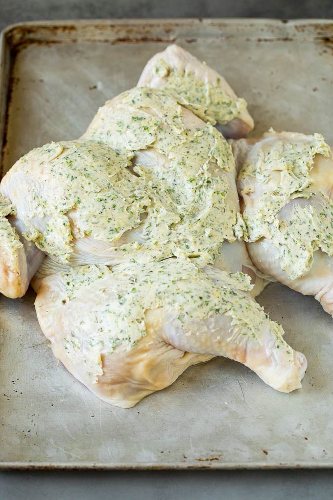 A flattened chicken coated in garlic and herb butter.