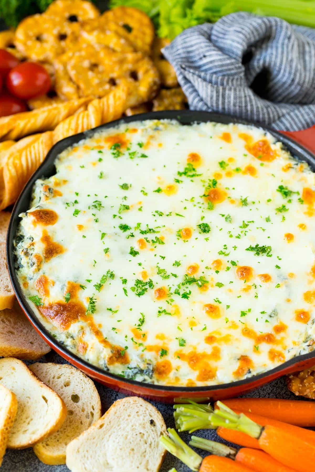 A pan of spinach artichoke dip topped with parsley.