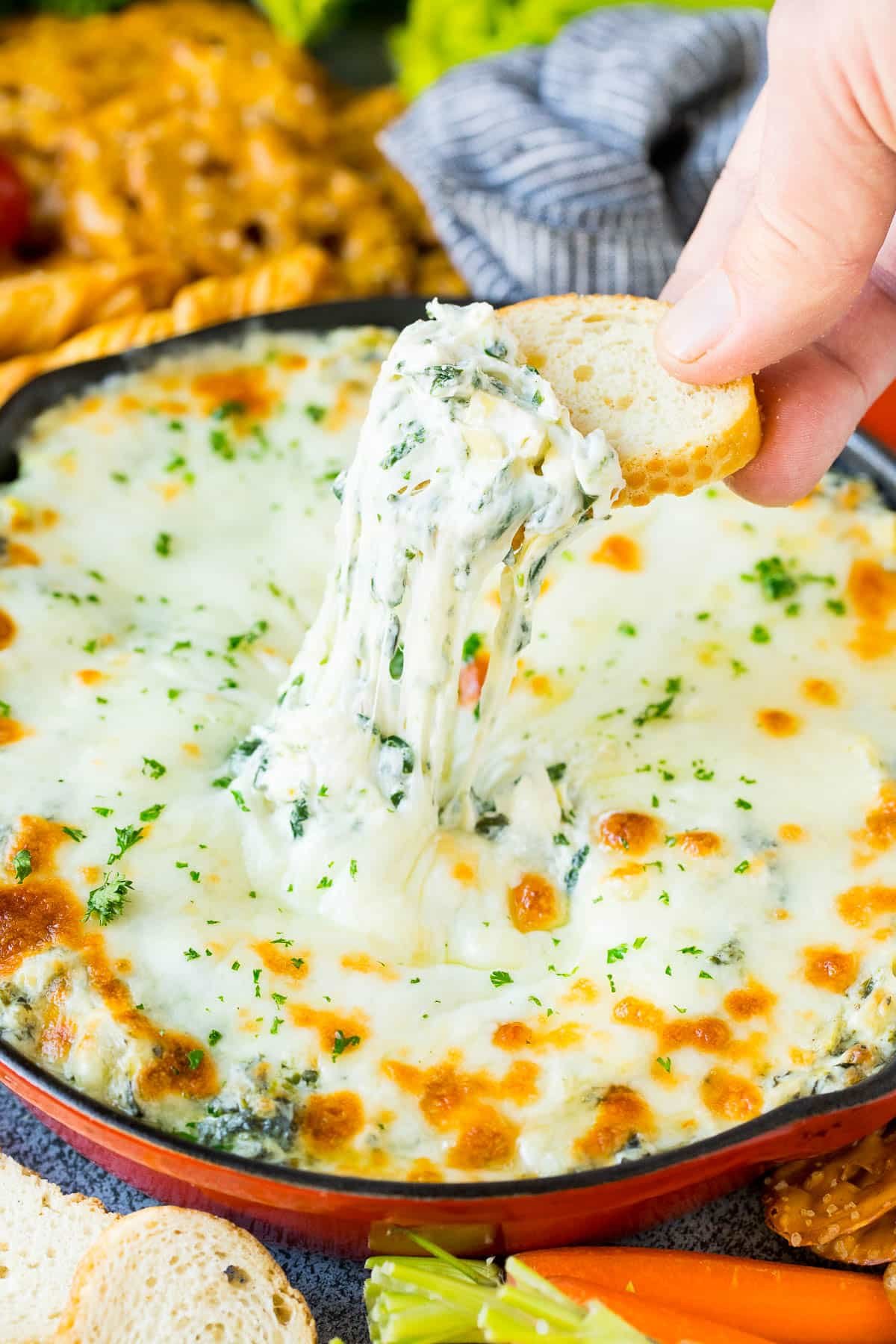 A slice of bread scooping up a serving of spinach artichoke dip.