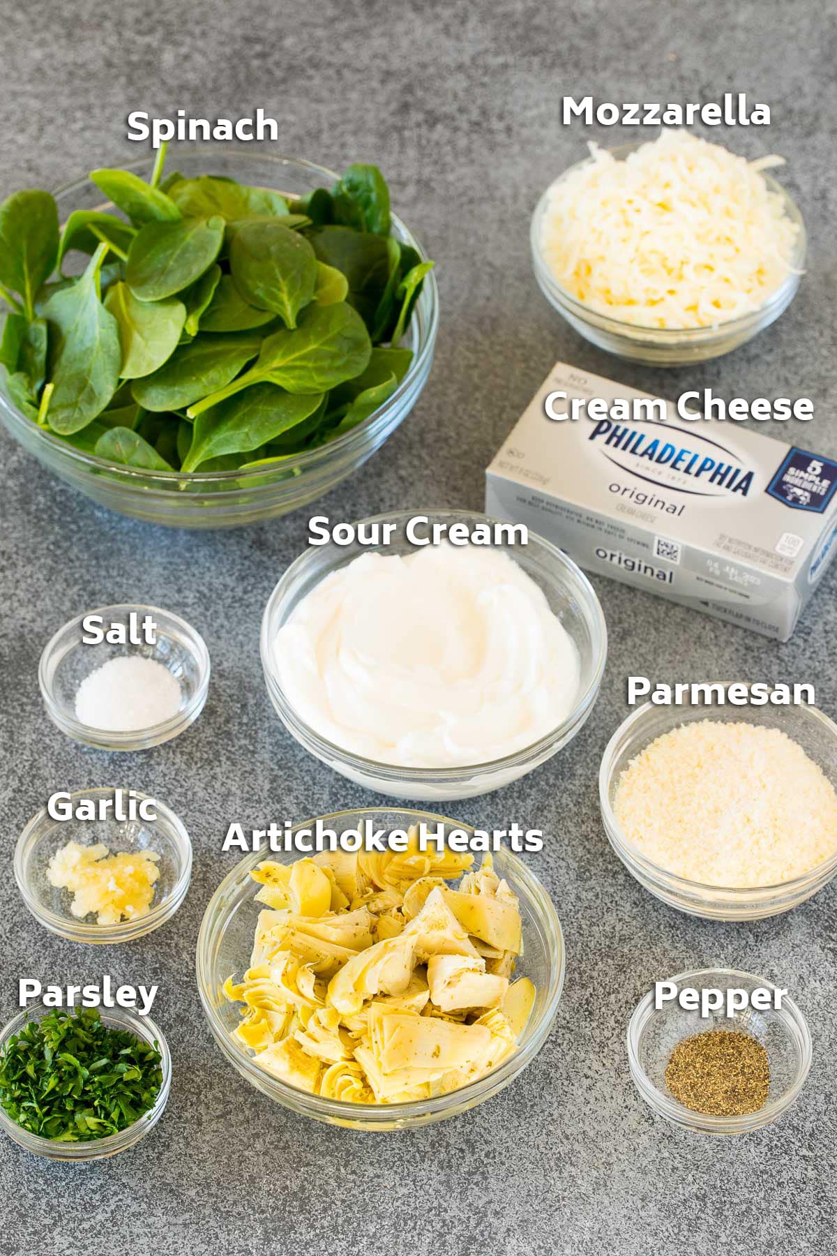 Bowls of ingredients including sour cream, cheese, spinach and artichokes.