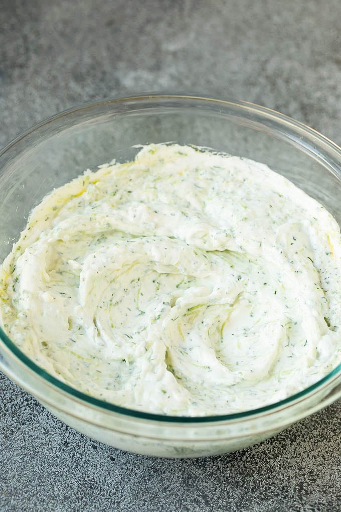 The best homemade tzatziki sauce with cucumber and herbs mixed into Greek yogurt. #appetizer #dinneratthezoo Tzatziki sauce in a glass bowl.