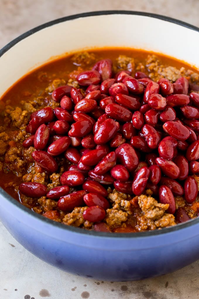 Kidney beans in a blue pot with a ground beef and tomato mixture.