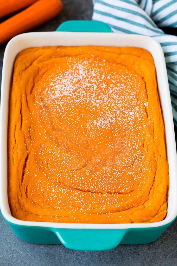 A baking dish of carrot souffle topped with powdered sugar.