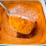 A spoon serving up a portion of carrot souffle.