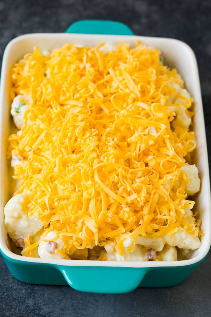 Cauliflower in a baking dish, topped with shredded cheese.