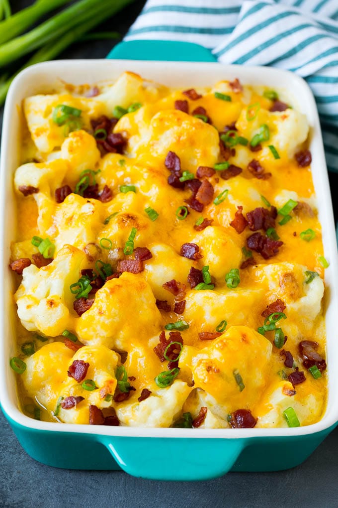 Cauliflower casserole topped with melted cheese, bacon and green onions.