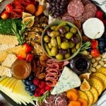 A charcuterie board filled with meats, cheeses, crackers, fruit and nuts.