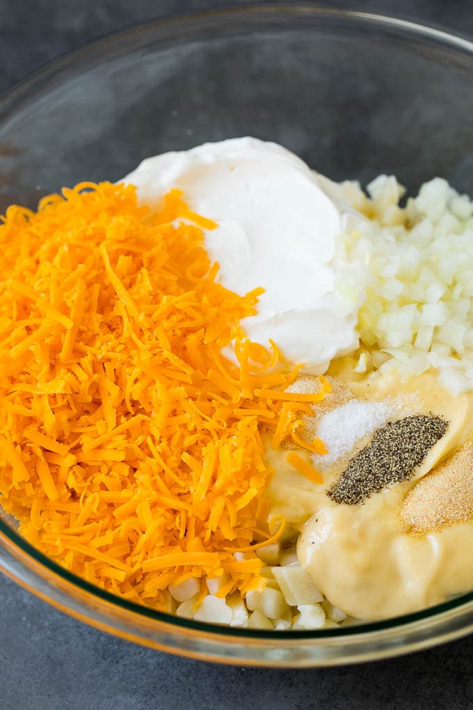 Diced potatoes, cream soup, shredded cheese and spices in a bowl.
