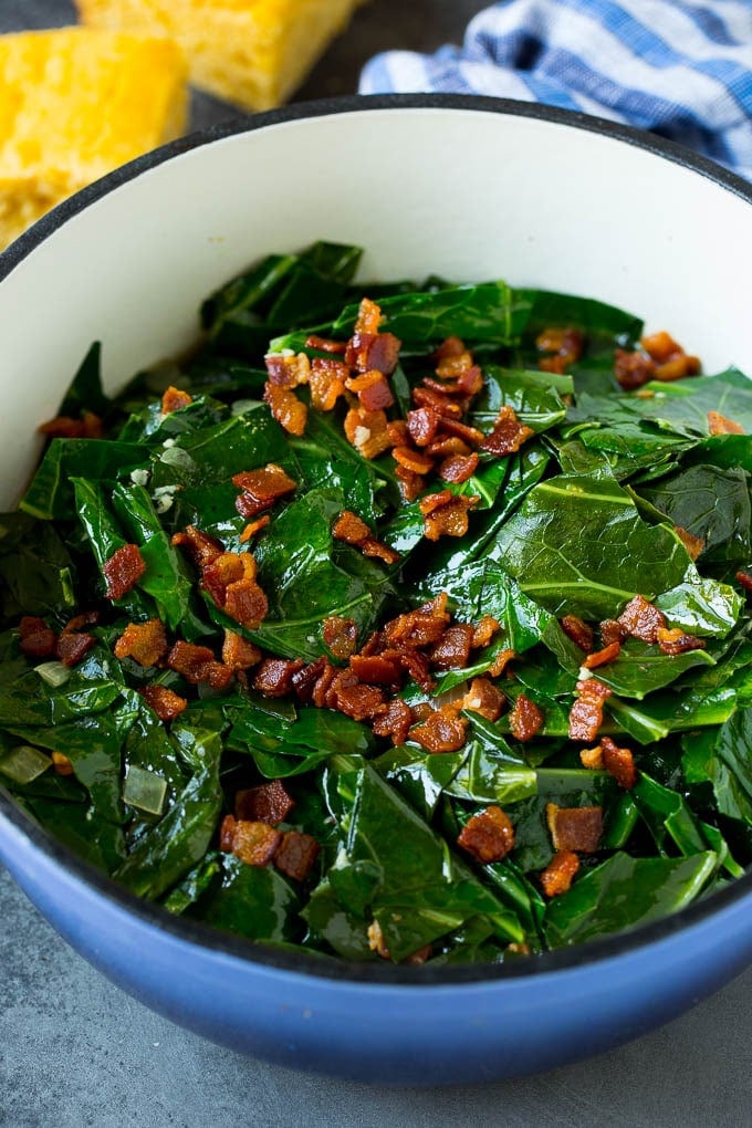 These Southern style collard greens are simmered with bacon and seasonings until tender and flavorful. A pot of collard greens topped with crispy bacon.
