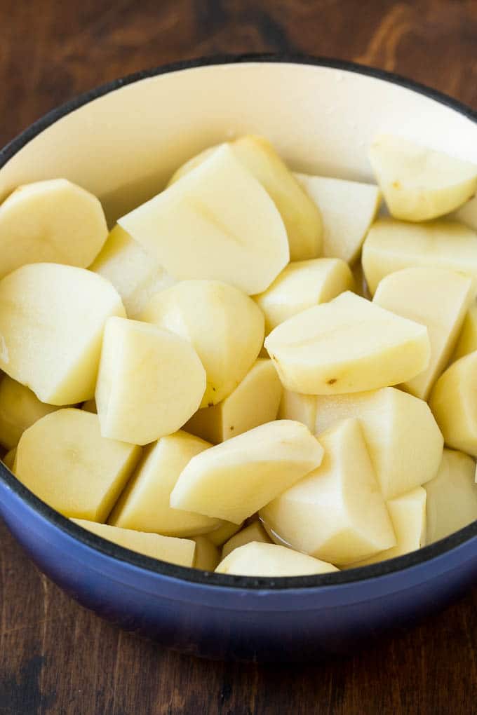 Peeled potato quarters in a pot of water.