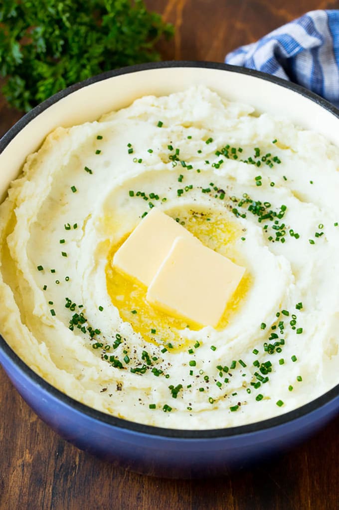 A pot of cream cheese mashed potatoes topped with butter and chives.