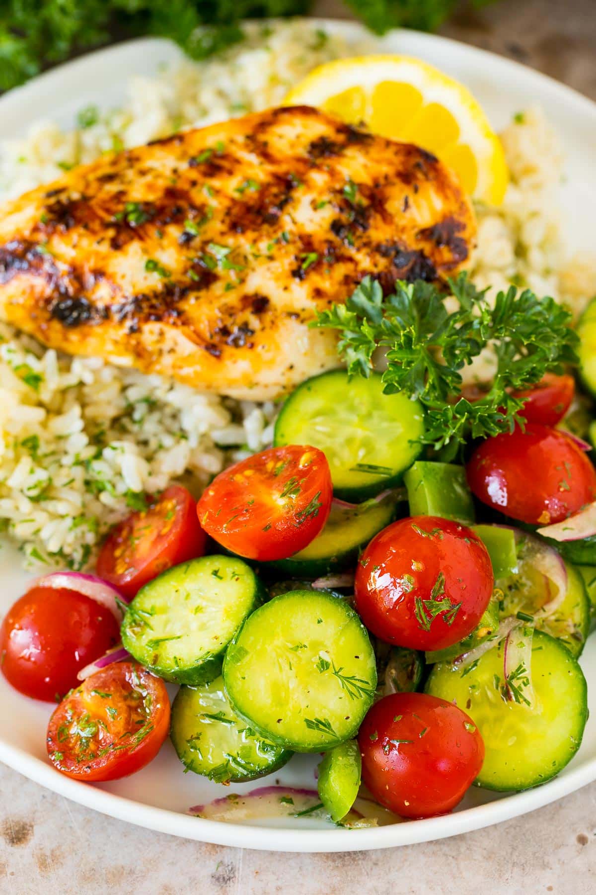 Cucumber tomato salad served with grilled chicken and rice.