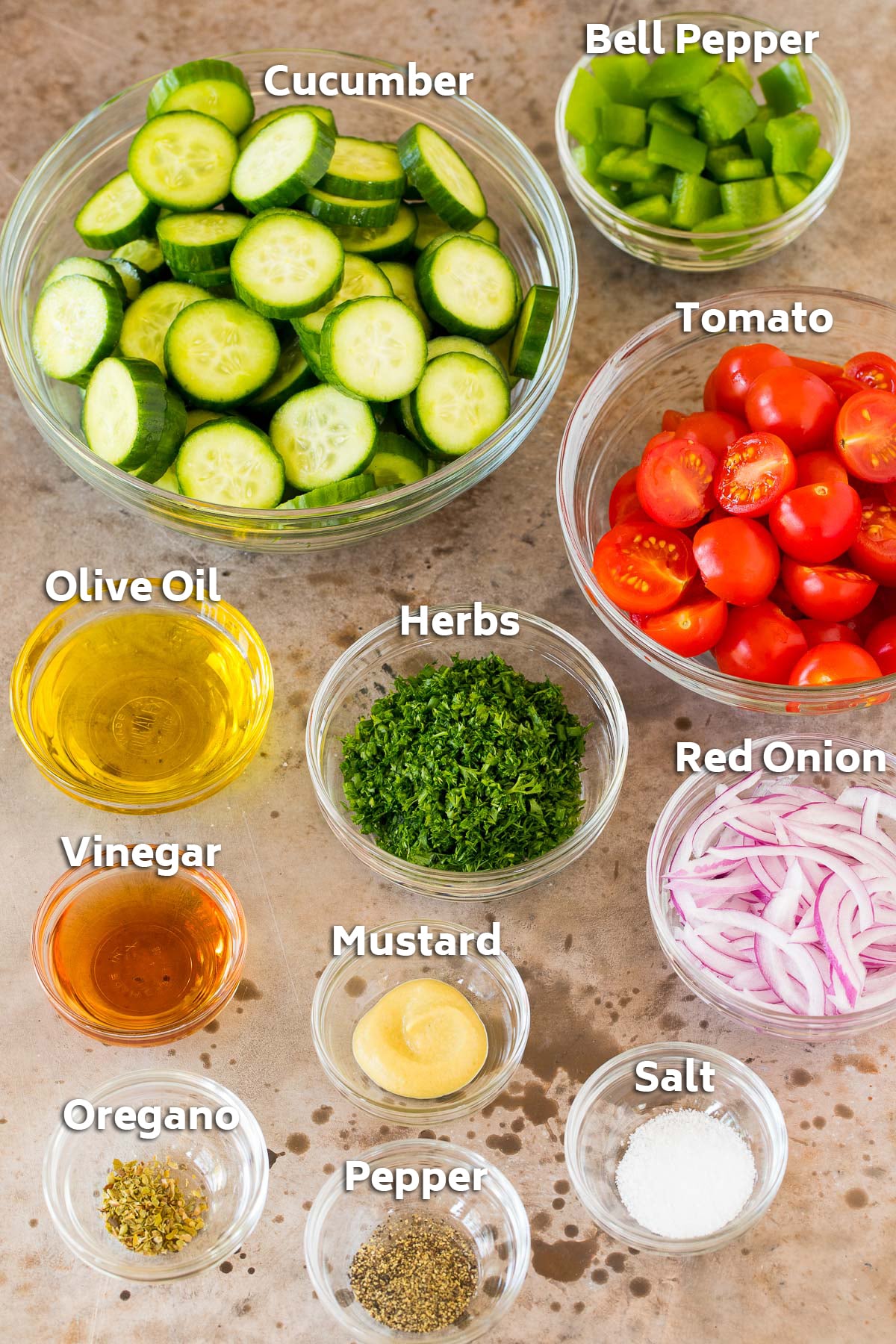 Ingredients in bowls including cucumber, tomato, herbs and seasonings.