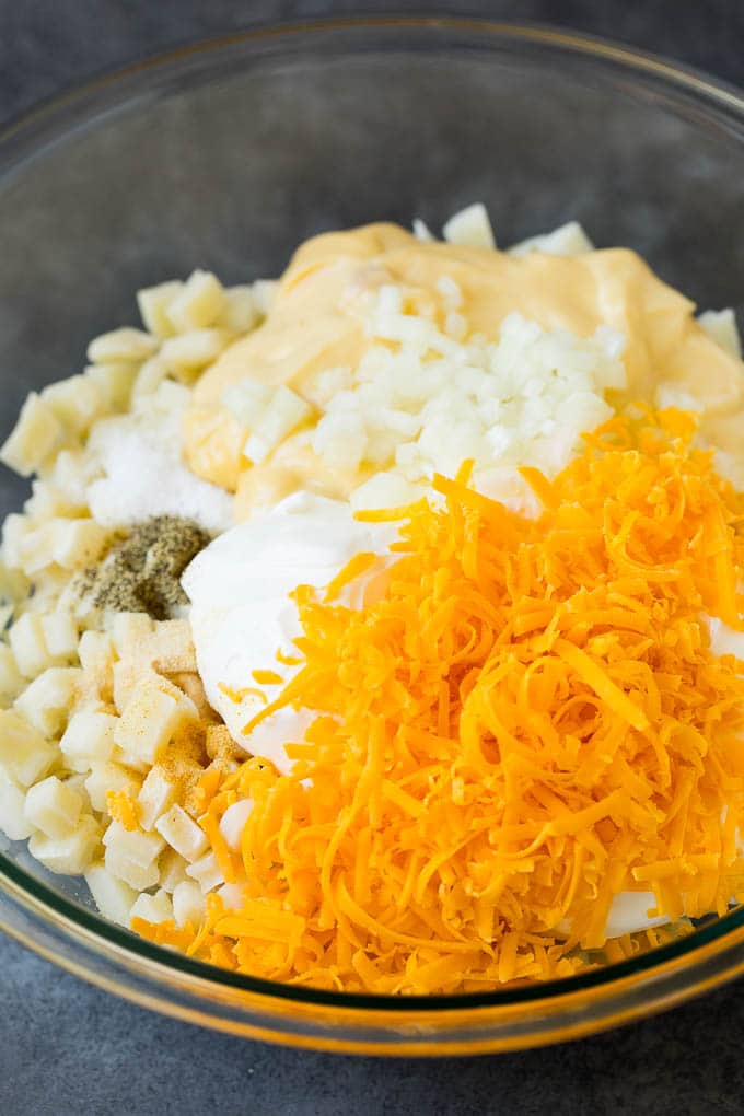 Potatoes, sour cream, grated cheese and seasonings in a bowl.