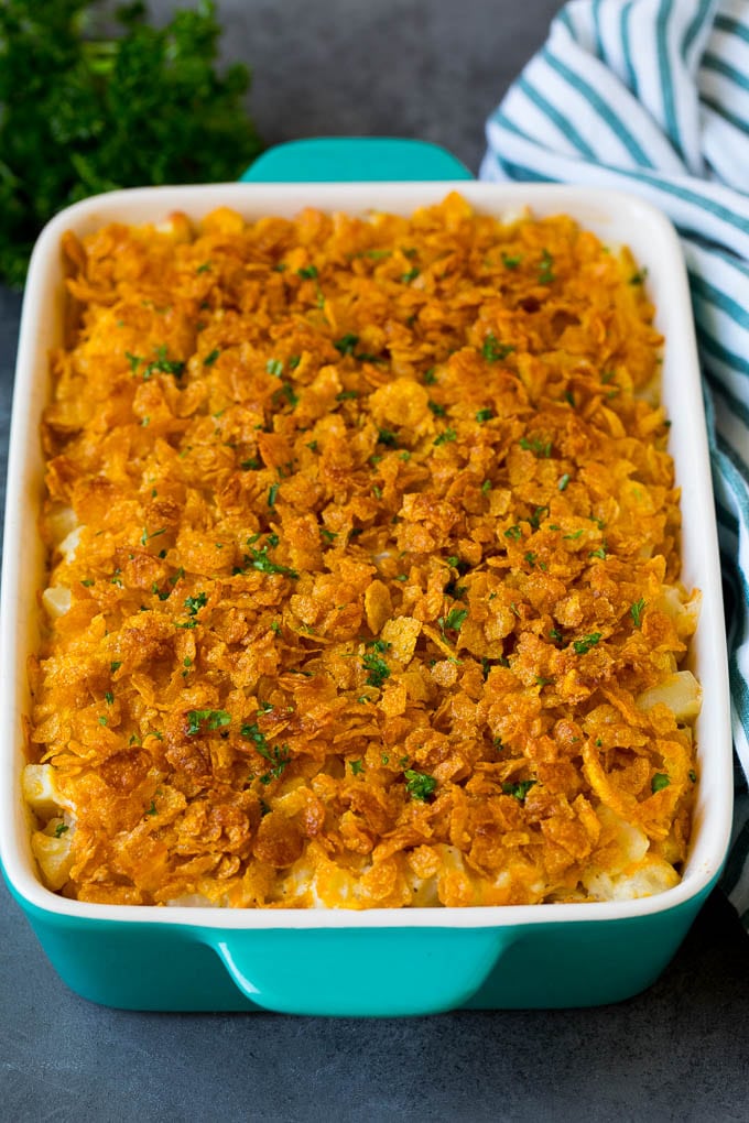 A dish of funeral potatoes topped with buttery cornflakes and parsley.