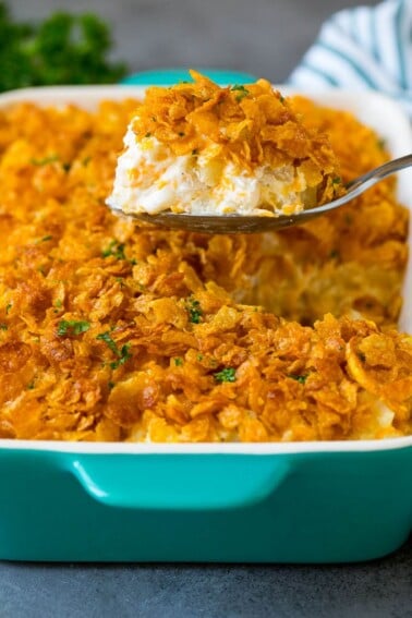 A spoon serving up a portion of cheesy funeral potatoes.