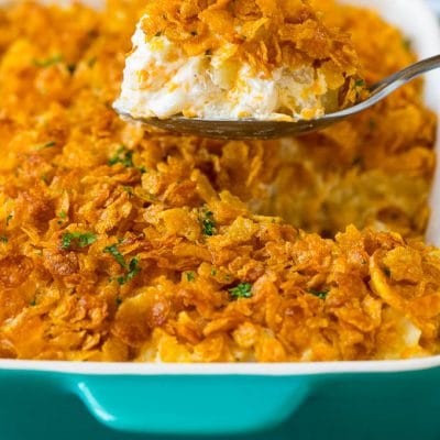 A spoon serving up a portion of cheesy funeral potatoes.