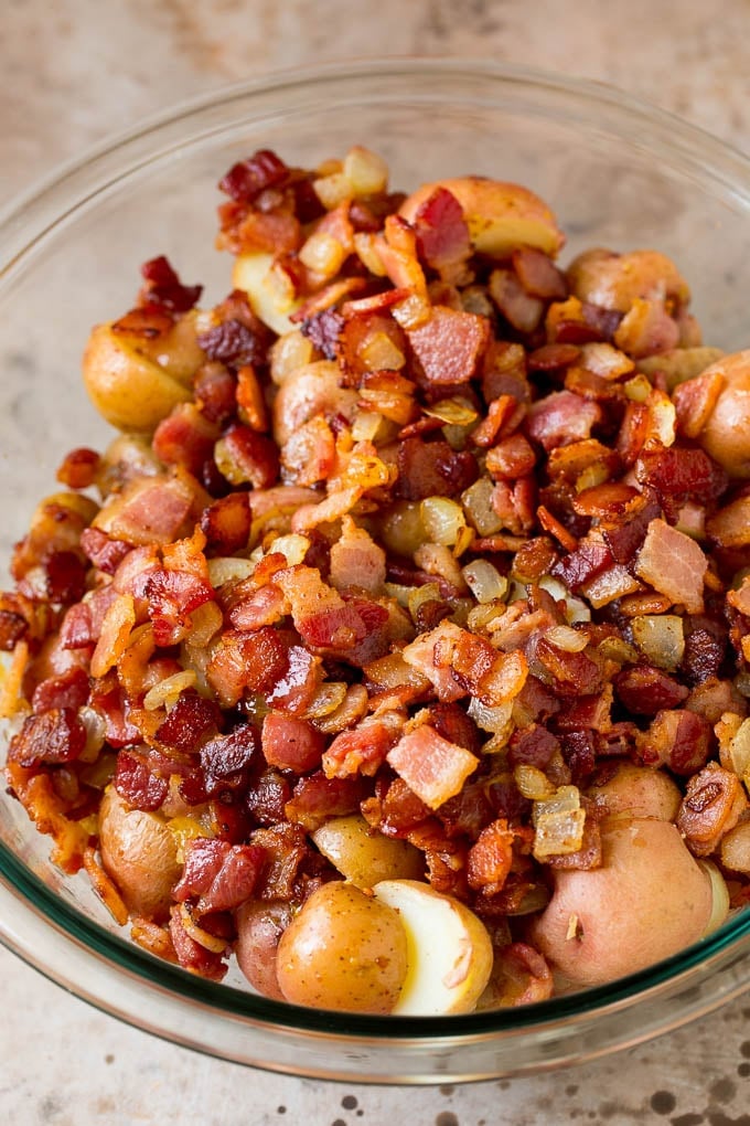 Cooked bacon and halved potatoes in a bowl.