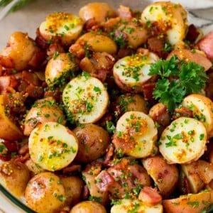 A bowl of German potato salad topped with fresh herbs.