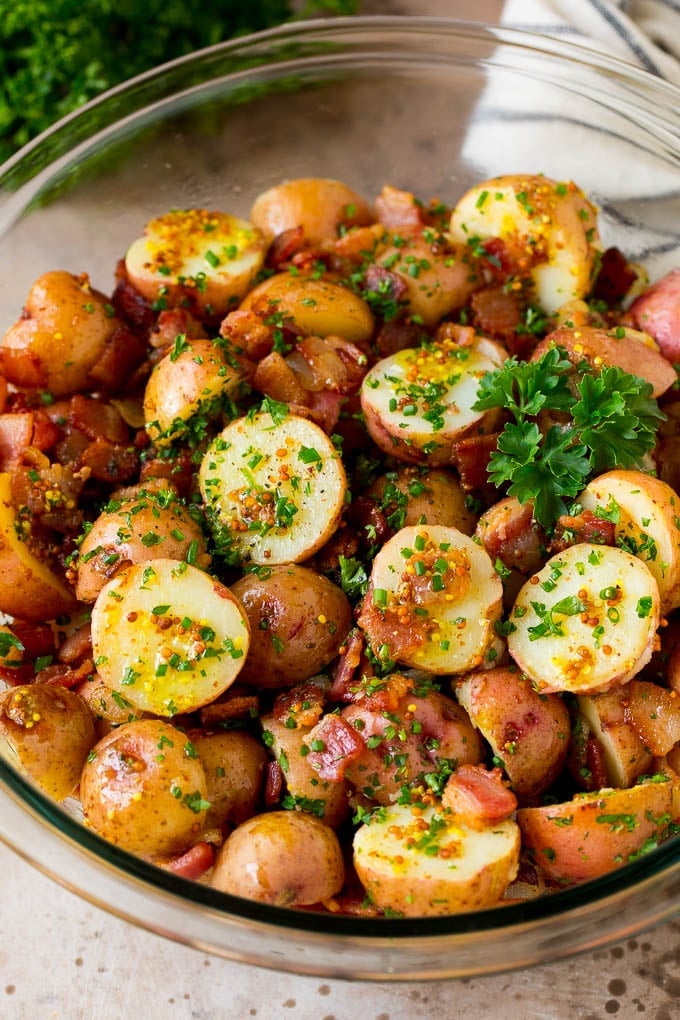 A bowl of German potato salad topped with fresh herbs.