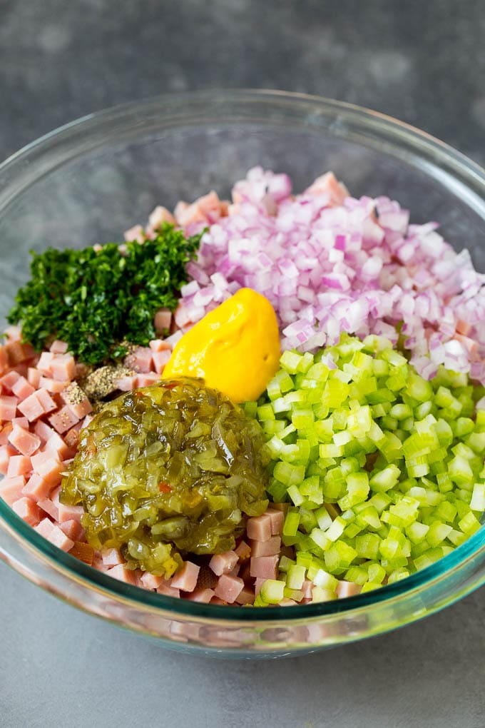 Finely chopped ham in a bowl with parsley, mustard, pickle relish and vegetables.