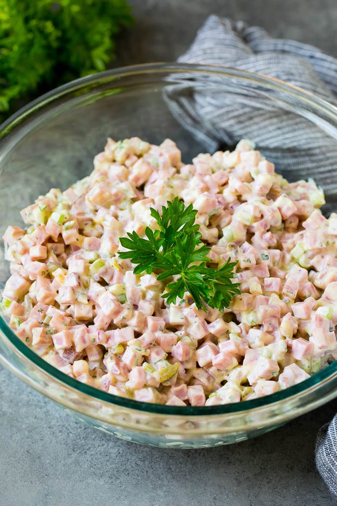 A bowl of creamy ham salad topped with parsley for garnish.