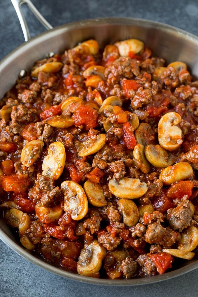 Ground beef, mushrooms, onions and tomatoes in a pan.