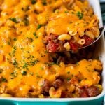 A spoon serving up a portion of hamburger casserole made with pasta and melted cheese.