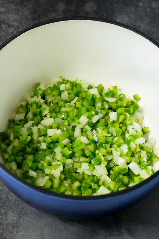 Onions, celery and bell peppers cooked in a pot.