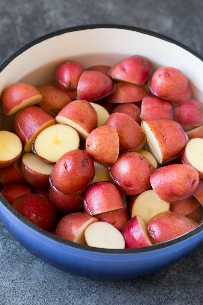 Halved red potatoes in a pot of water.