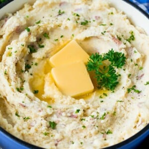 A pot of mashed red potatoes garnished with butter and parsley.