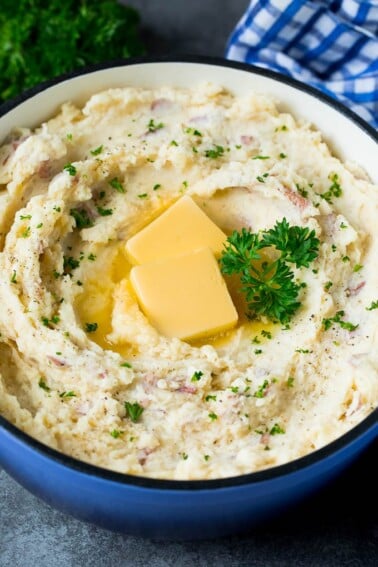 A pot of mashed red potatoes garnished with butter and parsley.