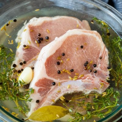 A bowl of pork chop brine with raw pork chops in it.