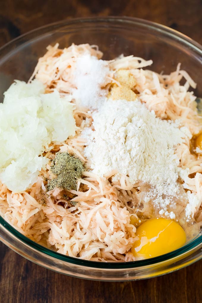 Shredded potatoes, eggs and seasonings in a bowl.