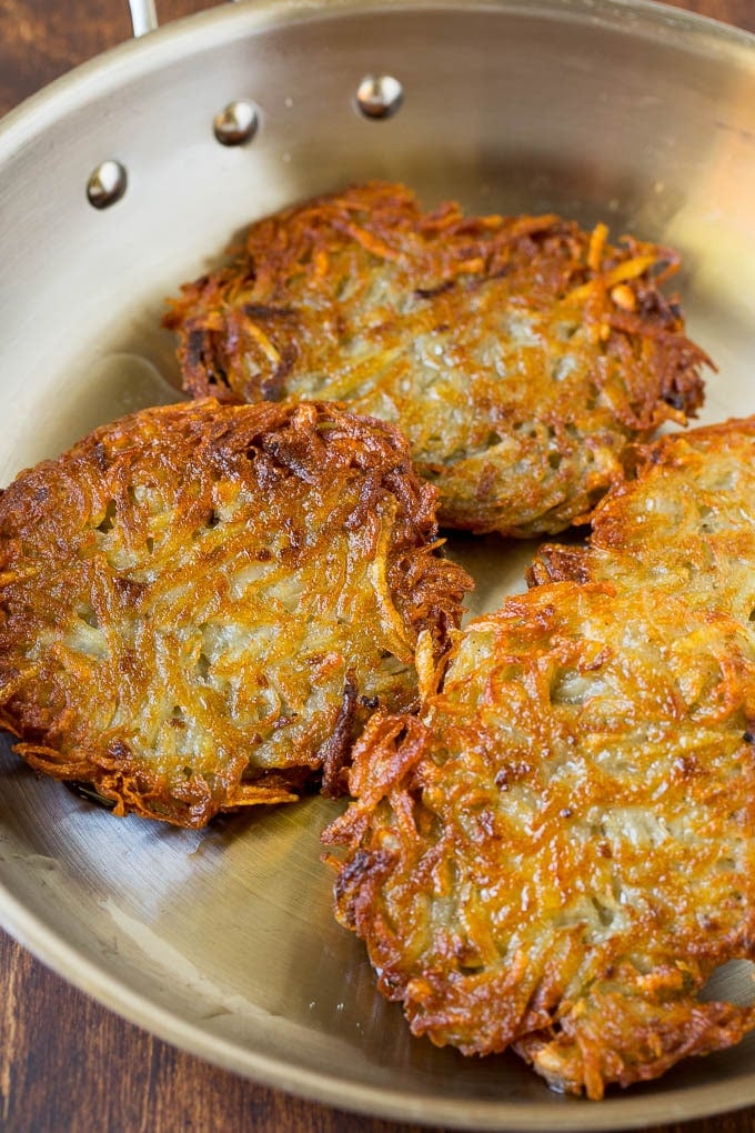 Cooked potato patties in a pan.