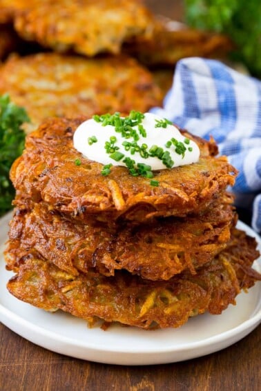 A stack of potato pancakes topped with sour cream and chives.