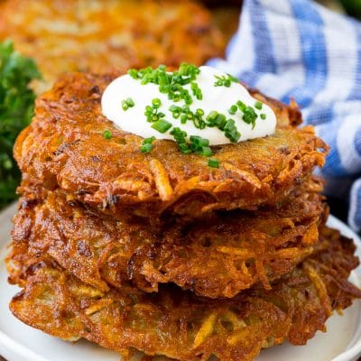 A stack of potato pancakes topped with sour cream and chives.