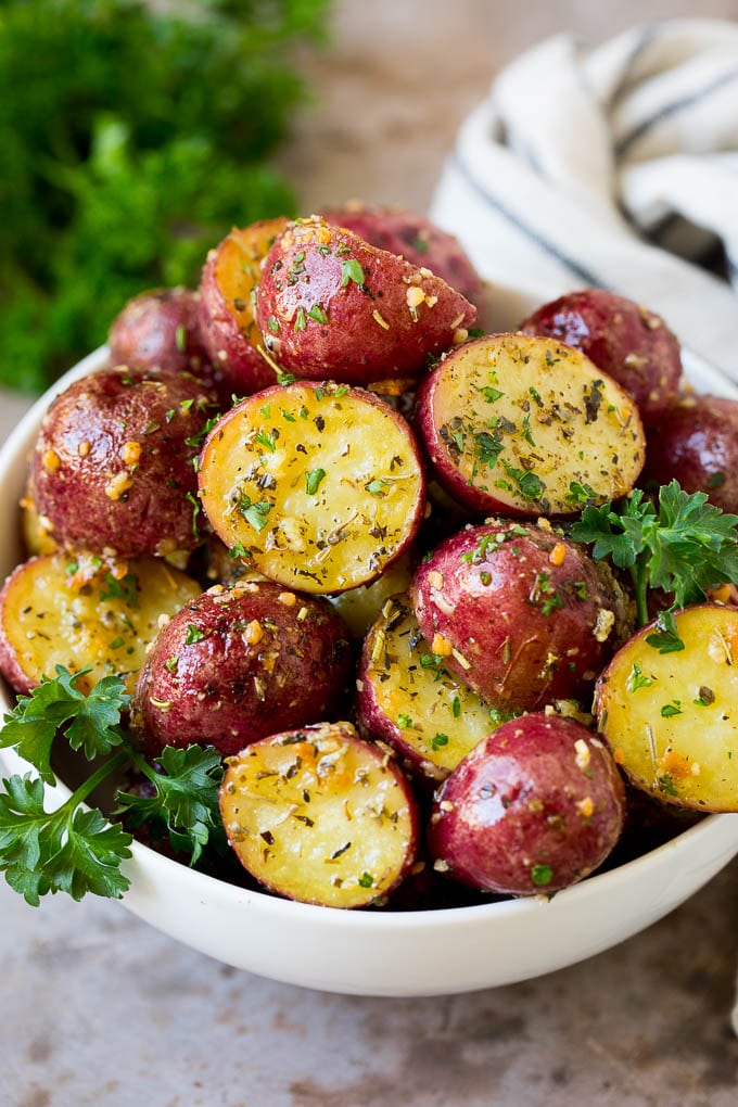 A bowl of roasted red potatoes garnished with fresh parsley.