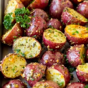 A sheet pan of roasted red potatoes coated in olive oil, herbs and garlic.