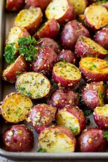 A sheet pan of roasted red potatoes coated in olive oil, herbs and garlic.