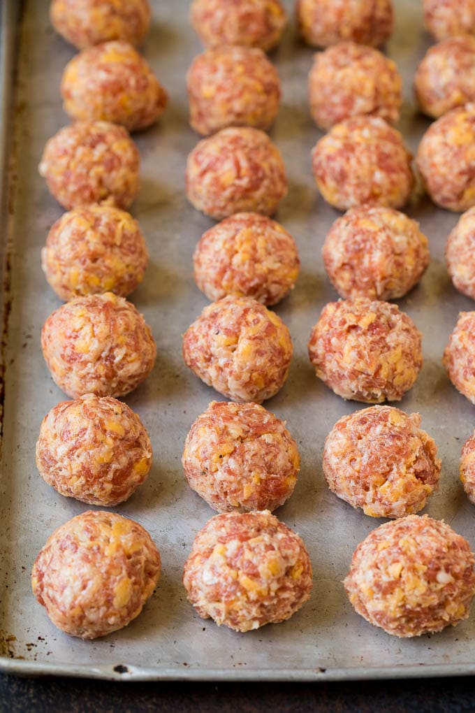 Balls of sausage and cheese mixture on a sheet pan.