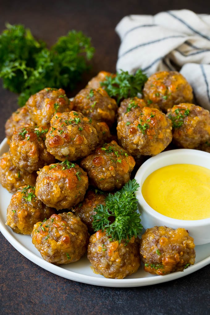 Sausage balls on a plate with a side of mustard sauce.