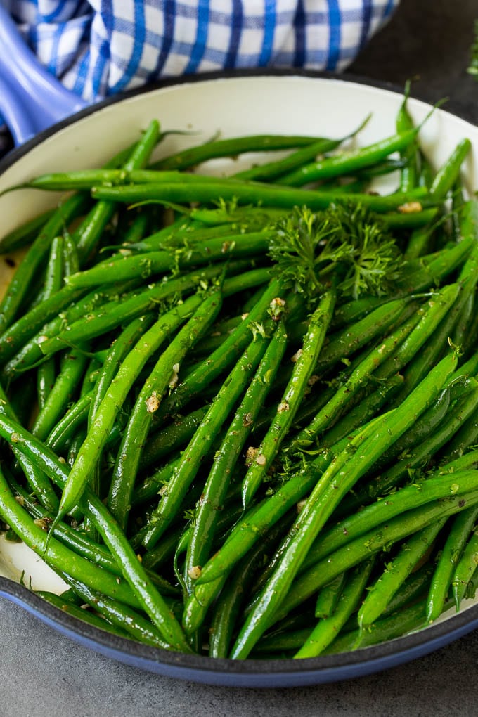 A blue skillet filled with sauteed green beans, garnished with parsley.