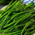 A plate of sauteed green beans with fresh parsley.
