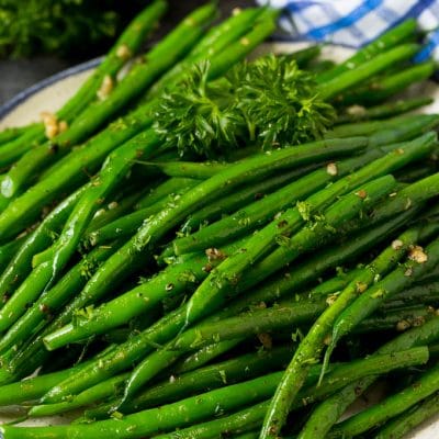 A plate of sauteed green beans with fresh parsley.