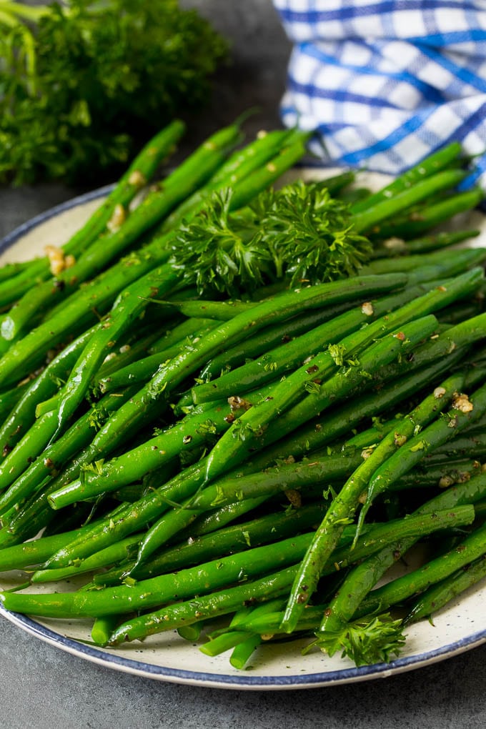 A plate of sauteed green beans with fresh parsley.