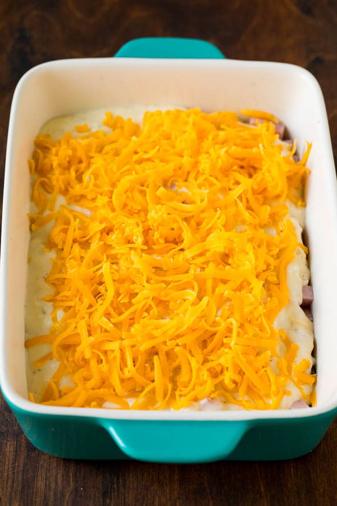 Layers of cheese sauce and shredded cheddar over sliced potatoes.