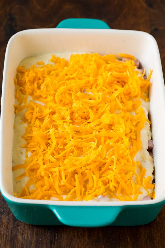 Layers of cheese sauce and shredded cheddar over sliced spuds.