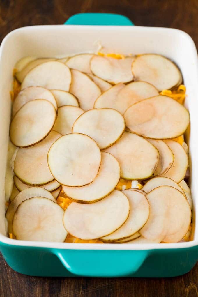 This scalloped potatoes and ham recipe is a layered casserole of thinly sliced potatoes in cheese sauce with diced ham, all baked together to golden brown perfection. Sliced spuds on top of layers of cheese and sauce.