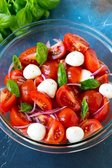 A bowl of tomato salad garnished with fresh basil.